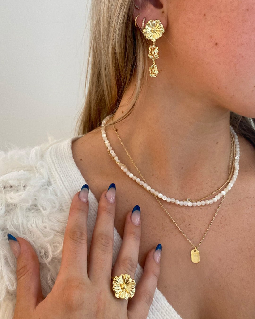 Stylist wearing gold plated statement earrings and rings. 