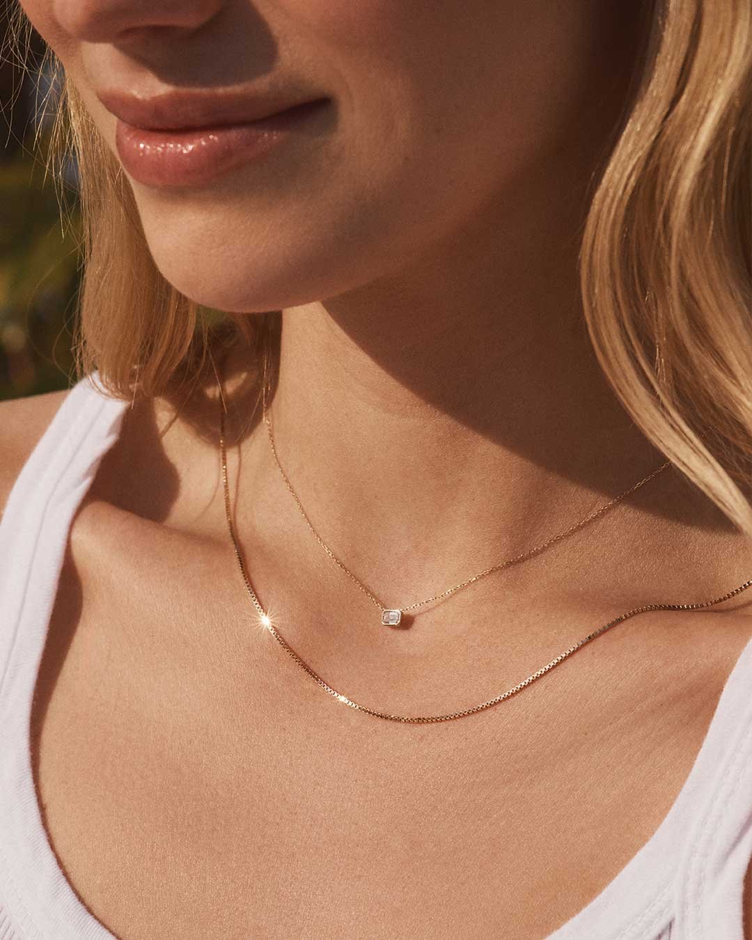 Woman wearing diamond pendant and gold chain necklace