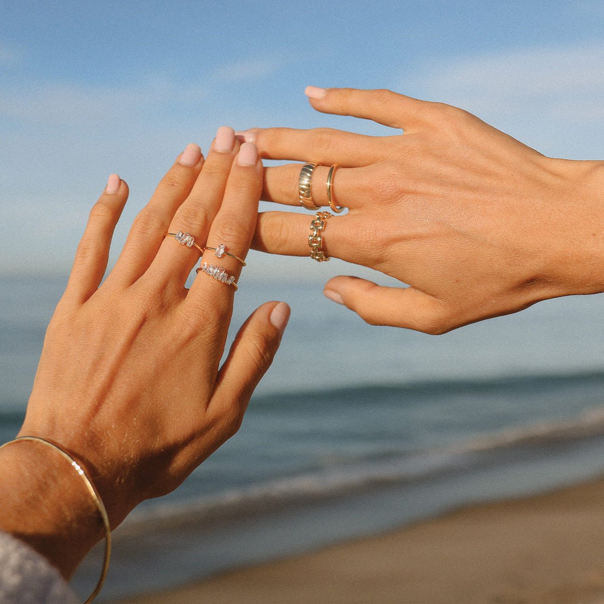 woman wearing gold plated rings by the ocean