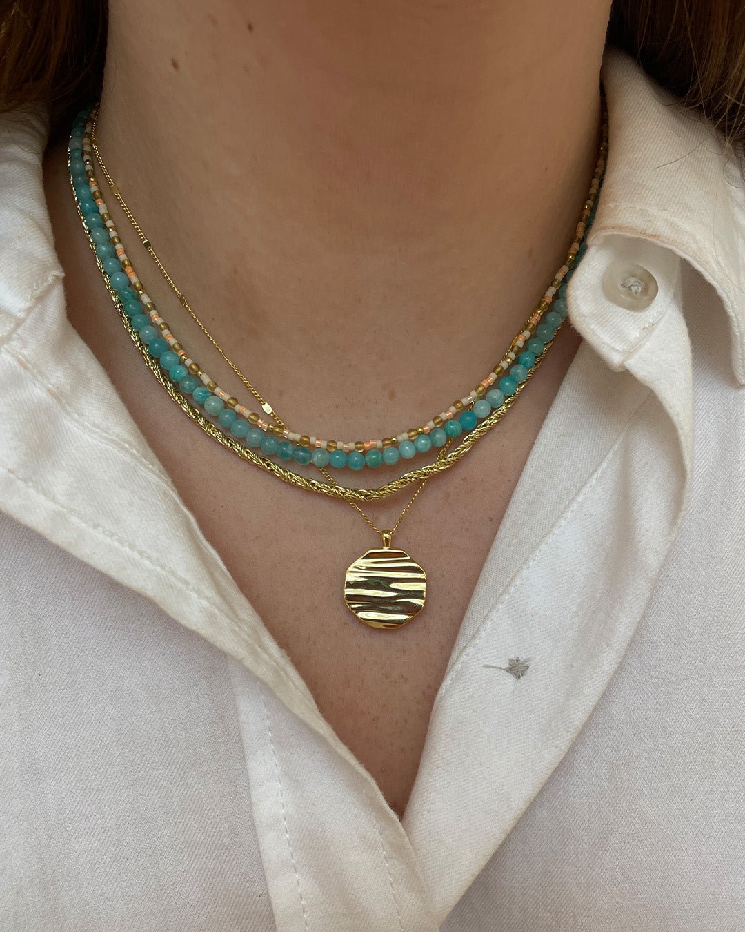 Stylist wearing gold plated and gemstone necklaces. 