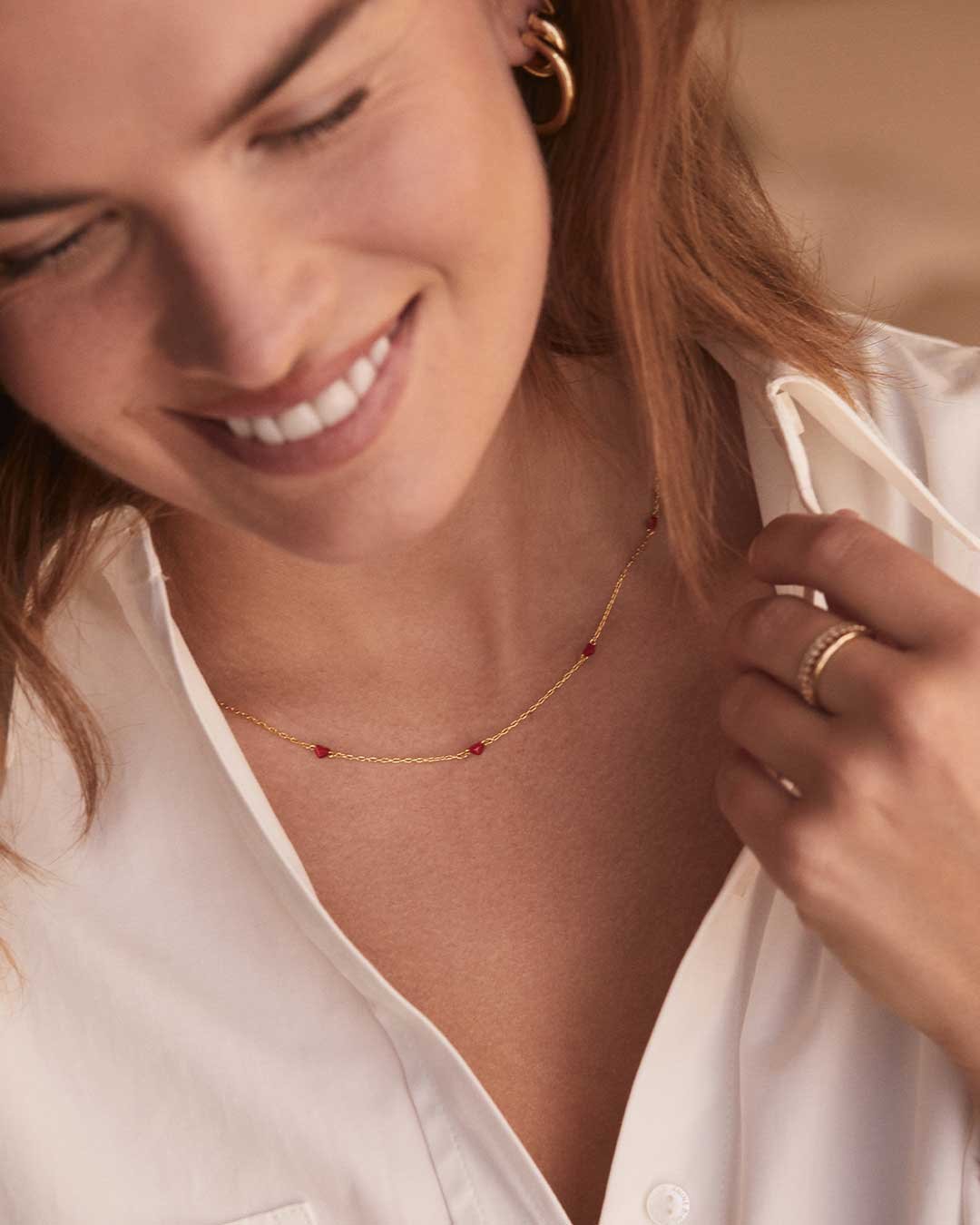 Woman wearing red heart necklaces and rings