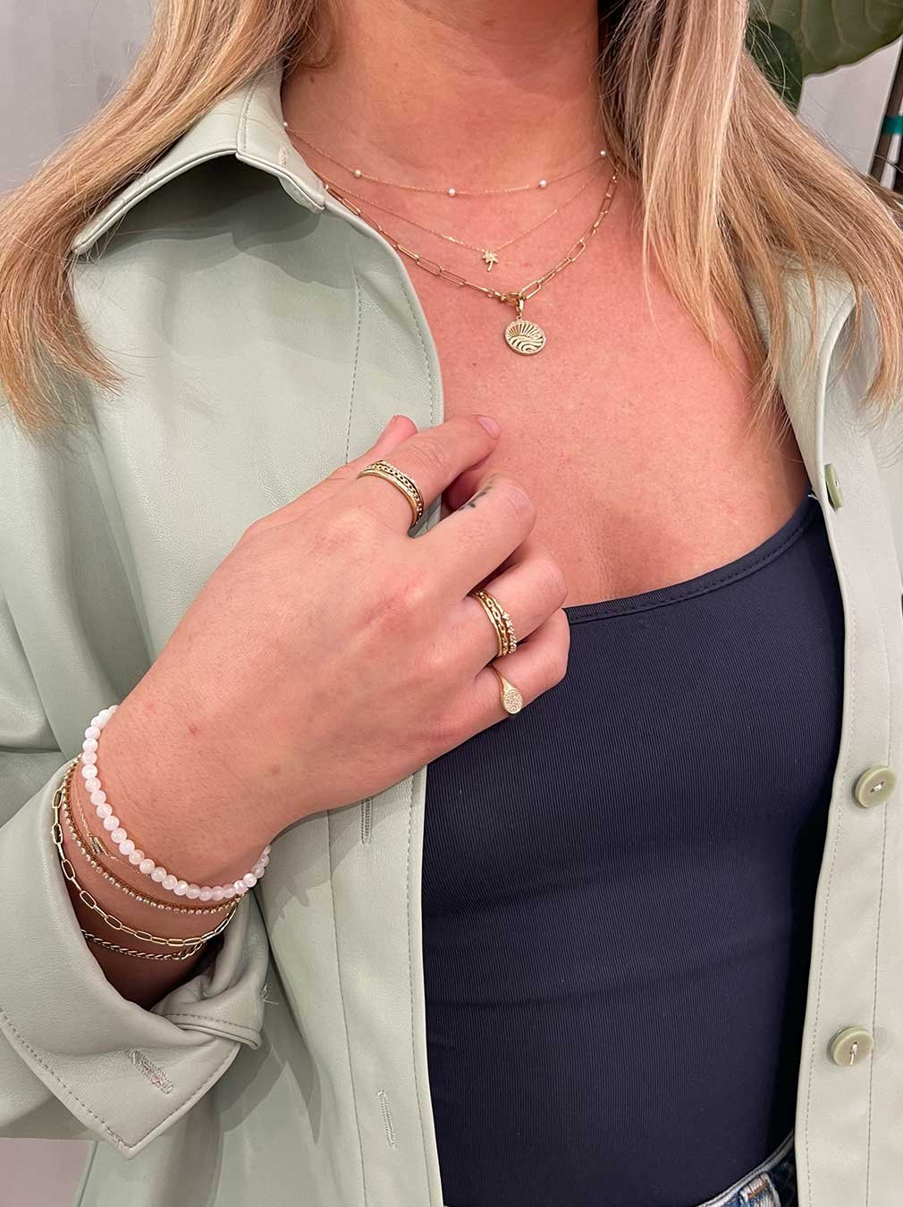 woman wearing gold plated and solid gold necklaces, bracelets and rings. 
