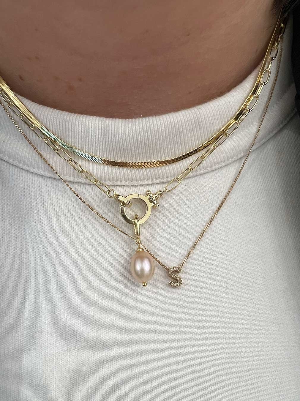 woman wearing gold plated and solid gold necklaces with charms. 
