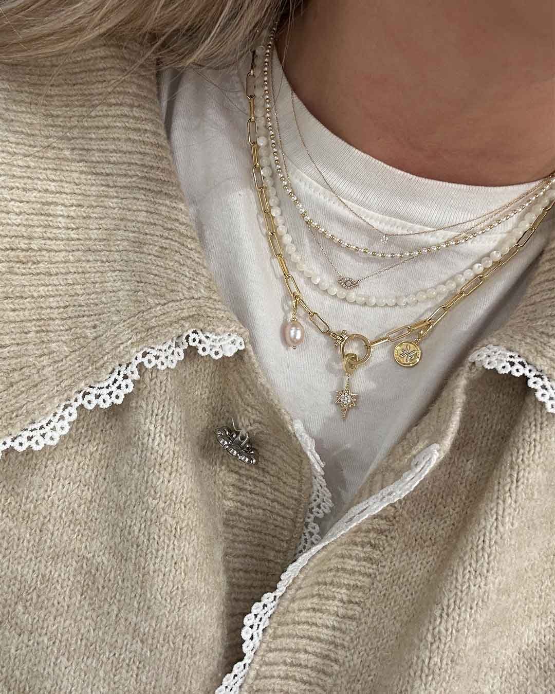 woman wearing pearl and chain link necklaces and charms