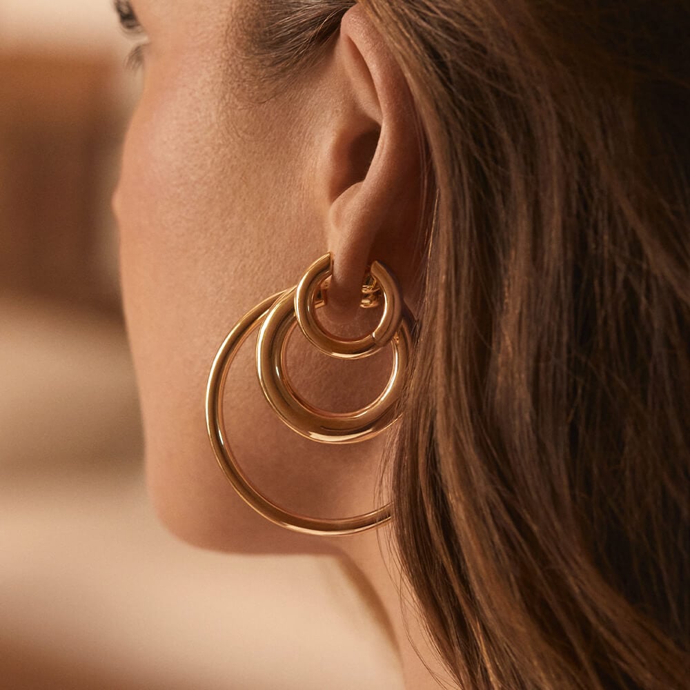 Woman wearing gold plated hoop earrings. 