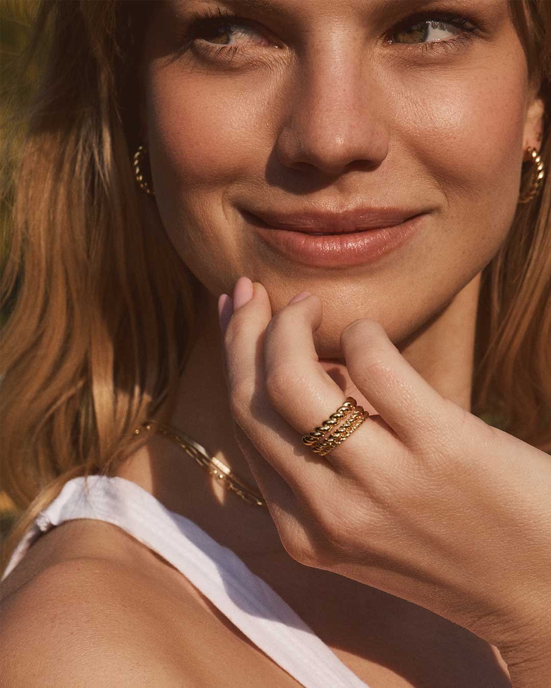 woman wearing gold plated twisted rings and hoops