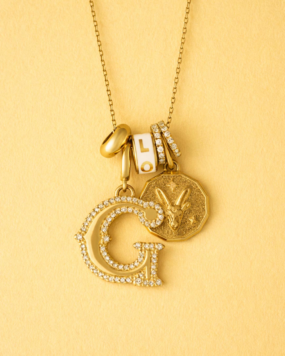Gold necklace with various pendants on a yellow background