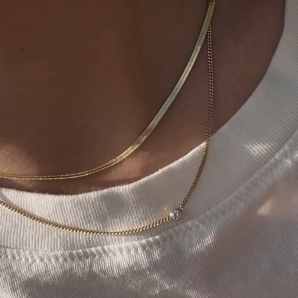 Woman in white tshirt with two gold necklaces on