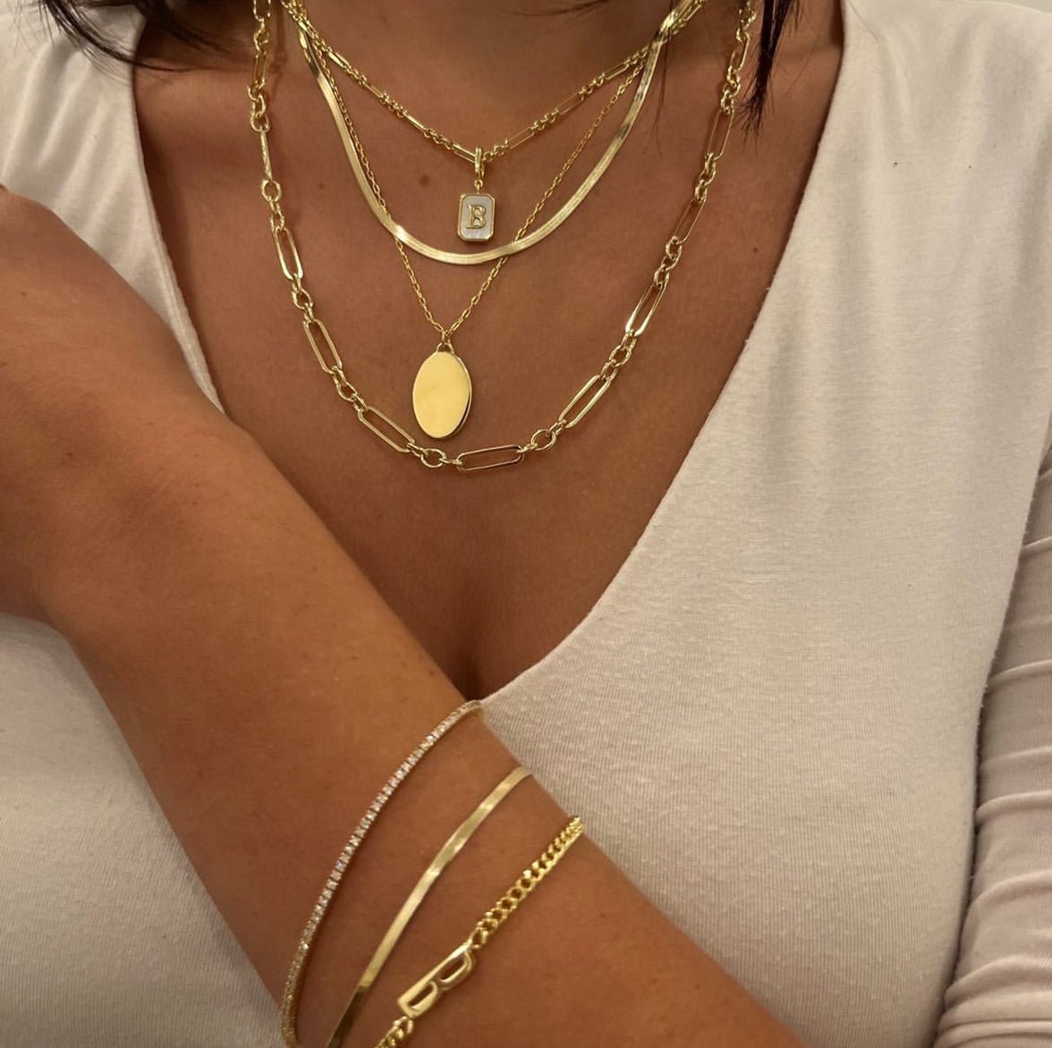 Woman wearing gold plated necklaces and bracelets with a diamond tennis bracelet