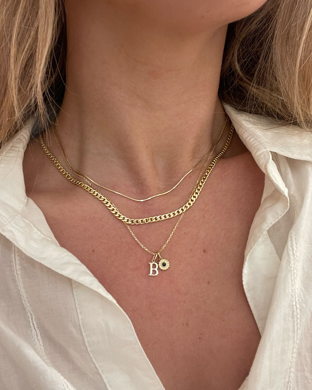 Woman wearing solid gold and gold plated necklaces and charms