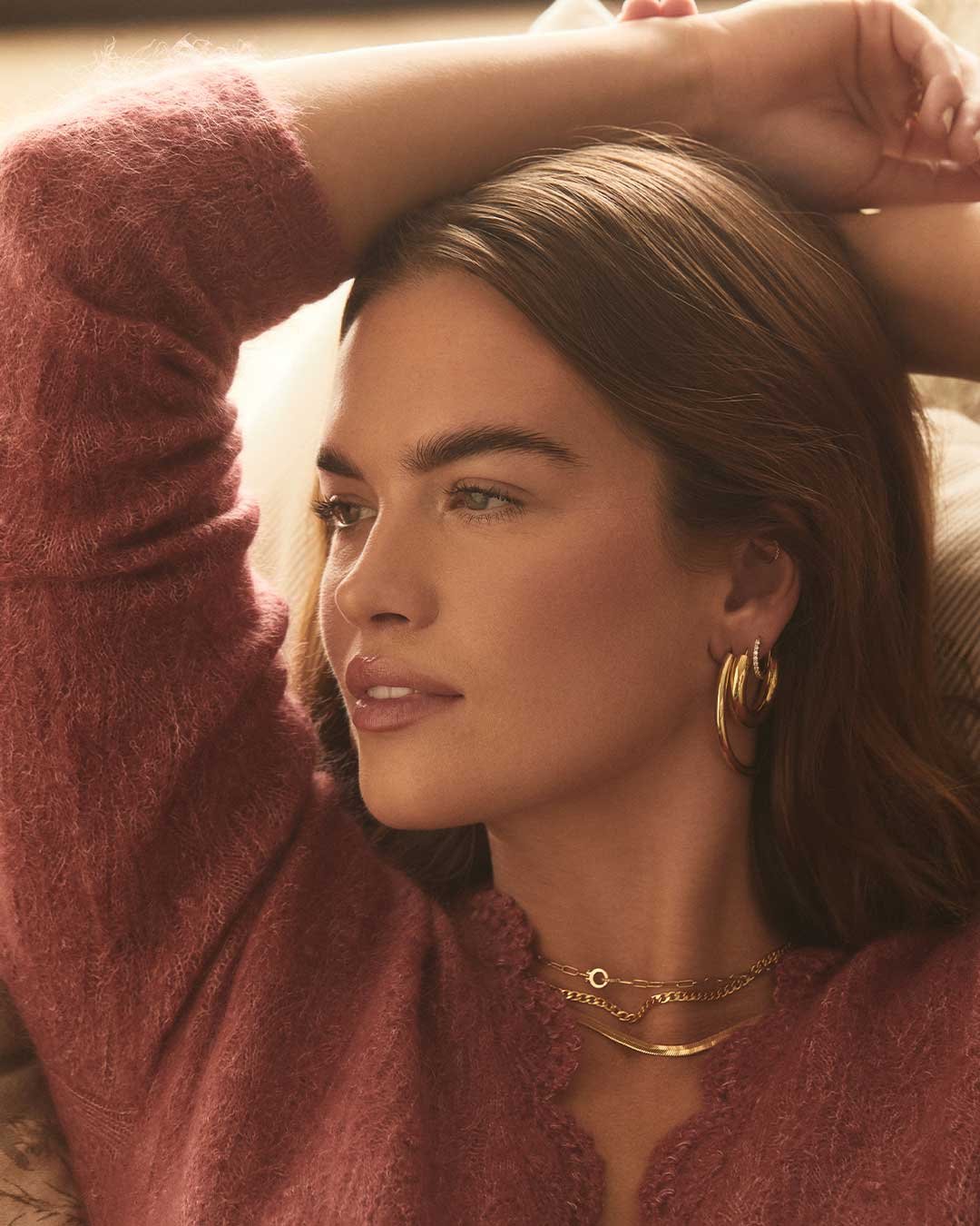 Woman wearing gold plated hoops and chain necklaces