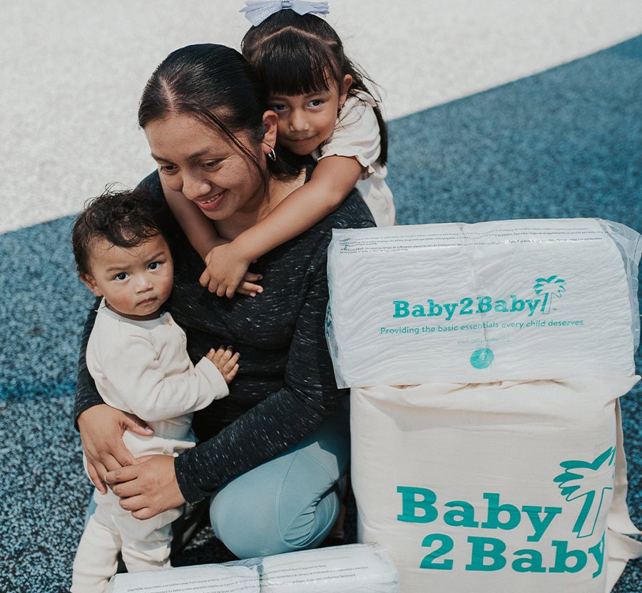 Mom with her two children and diapers given by Baby2Baby.