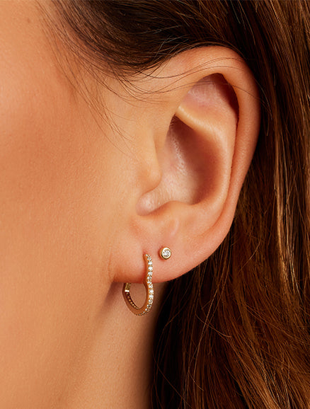 Woman wearing diamond heart huggies. Shop Earrings