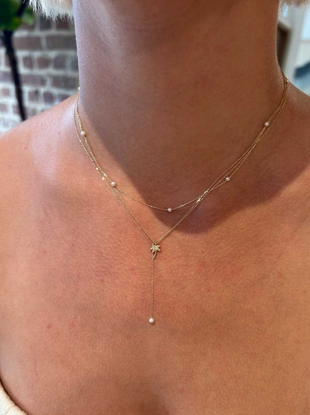 woman wearing pearl and diamond charm necklaces