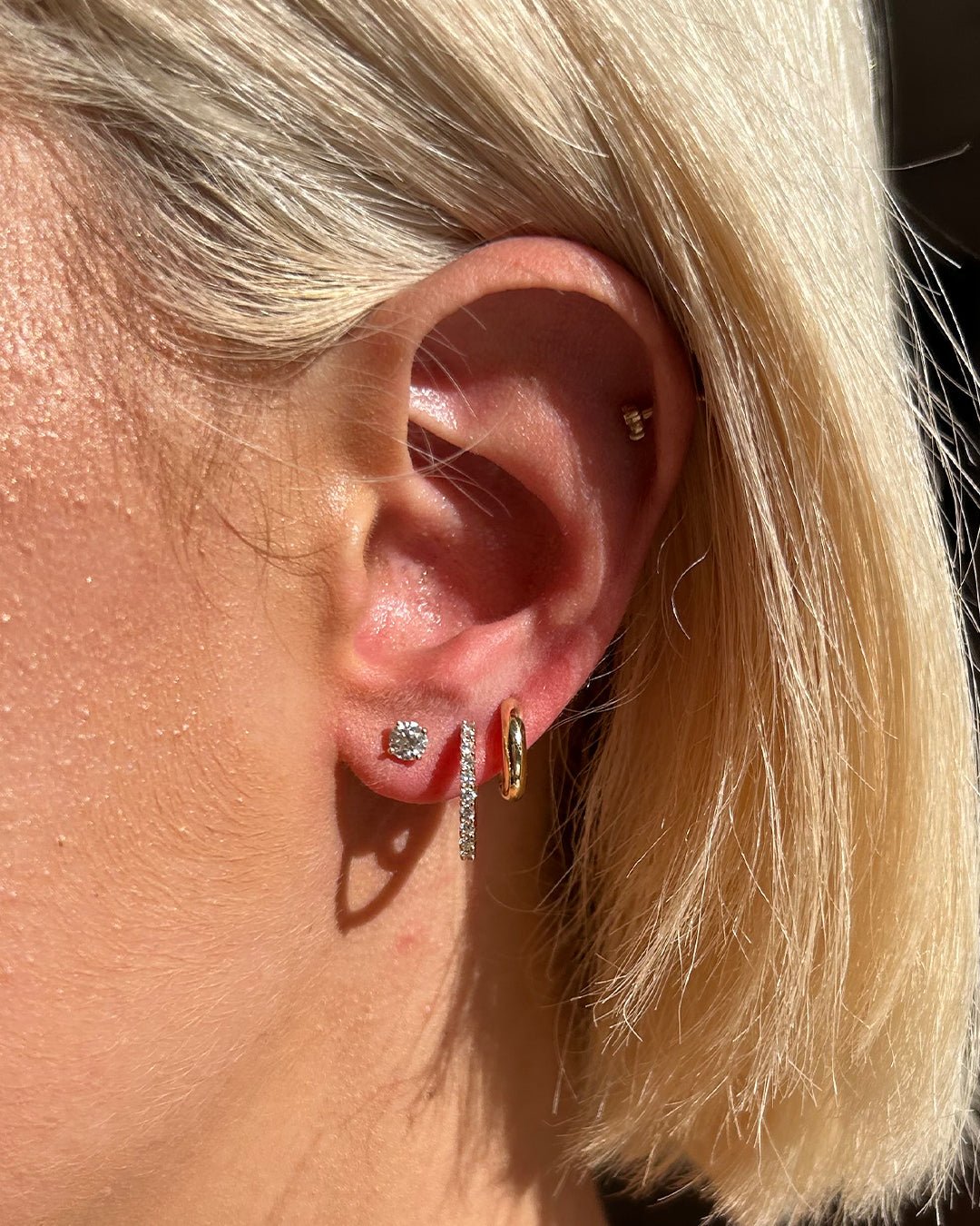 Woman wearing 14k gold hoops and diamond studs and hoops. 