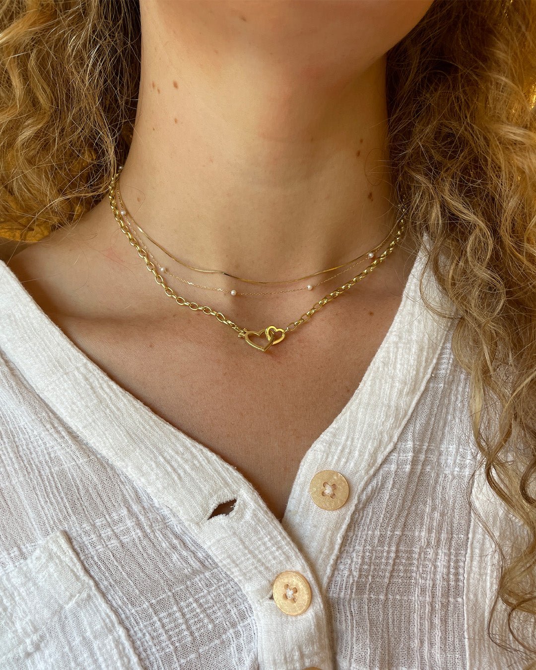 Woman wearing 14k gold necklaces and a gold plated heart necklace. 