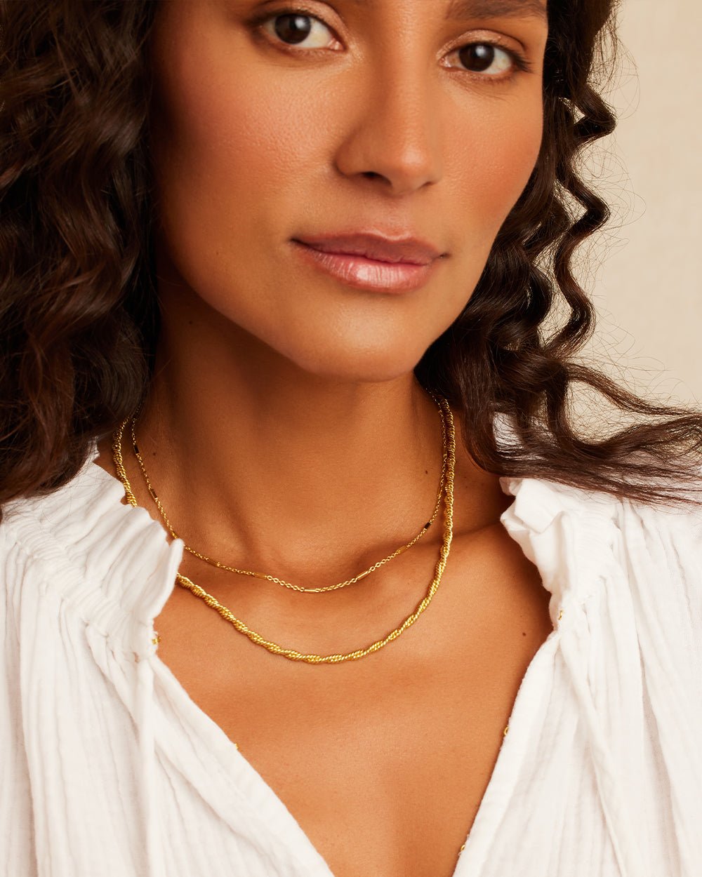 Woman wearing gold plated necklace layered set. 