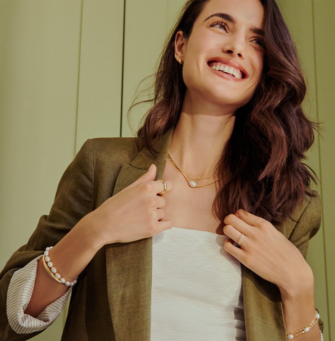 woman in olive green blazer adorned with pearl bracelet and necklace