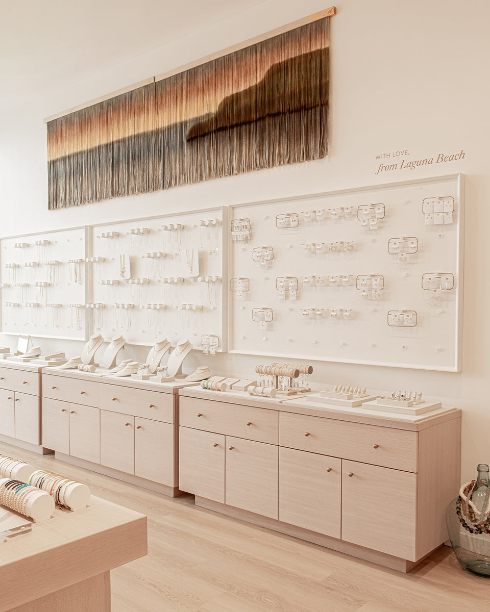 inside of gorjana store with jewelry on walls and white washed cabinets with jewelry displayed on top