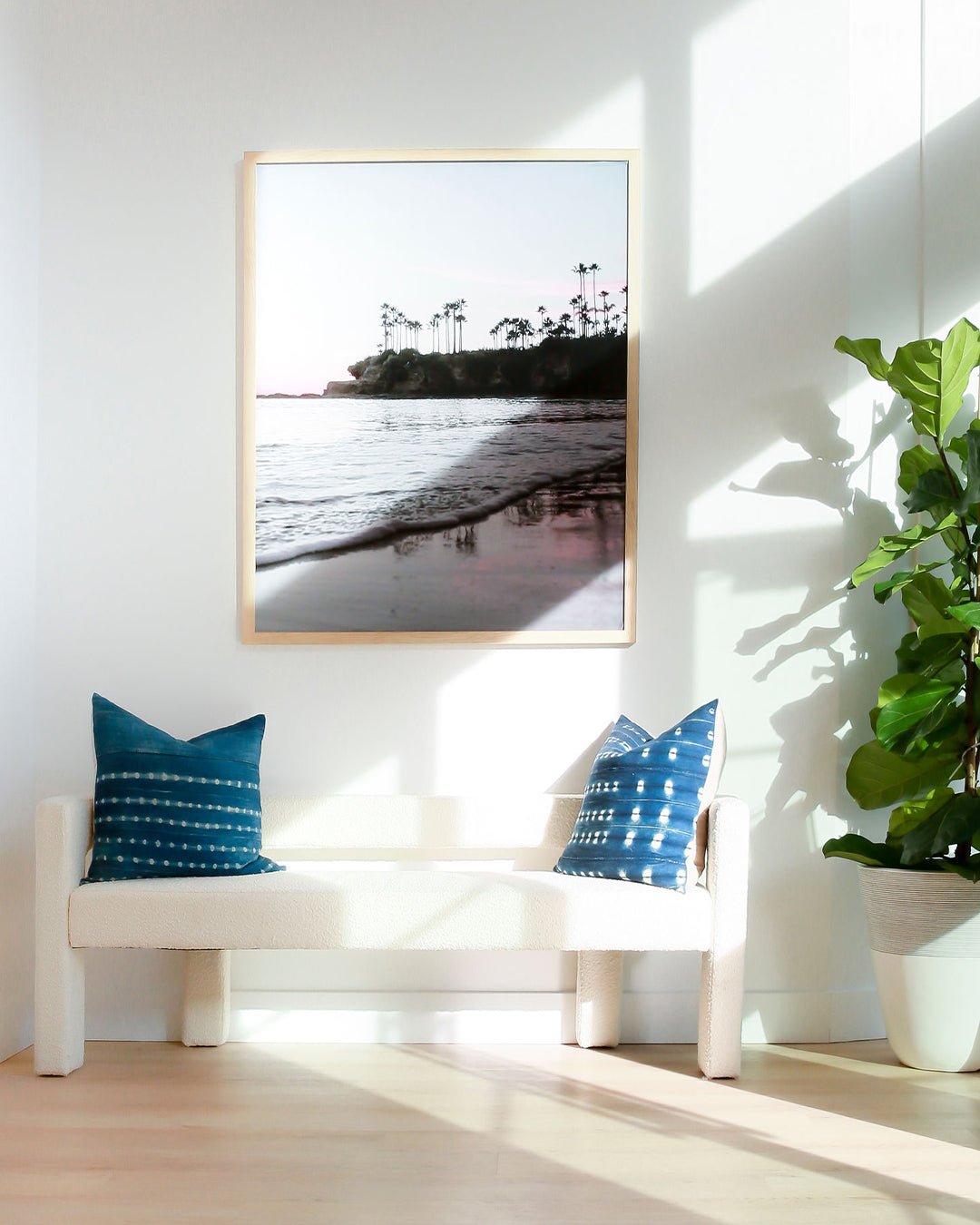 beachy interior with a framed image of laguna beach and a bench underneath