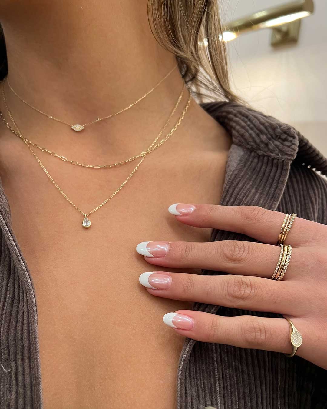 Stylist wearing The Diamond Evil Eye Necklace, 14k Gold Parker Micro Mini Necklace, White Sapphire Pear Charm Necklace, Diamond Row Ring, Diamond Lou Helium Ring, Diamond Pave Signet Ring