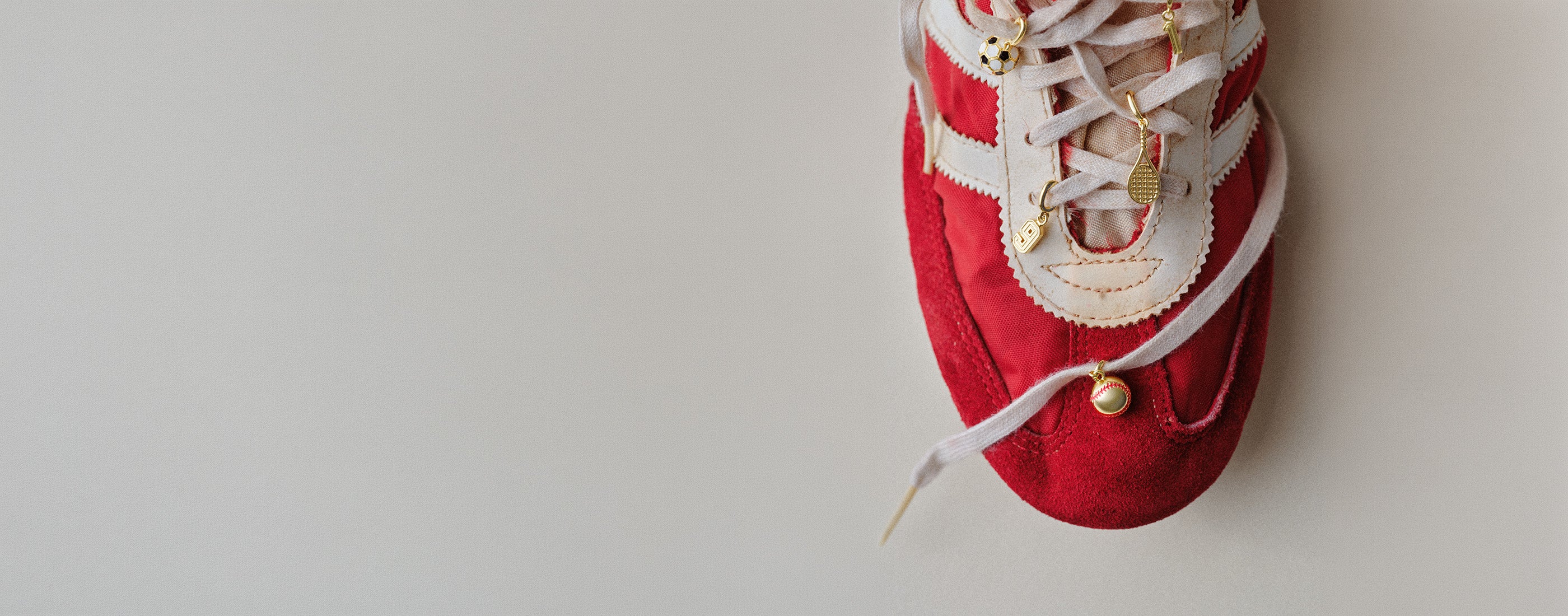 Red sneaker with gold plated sports and number charms on it