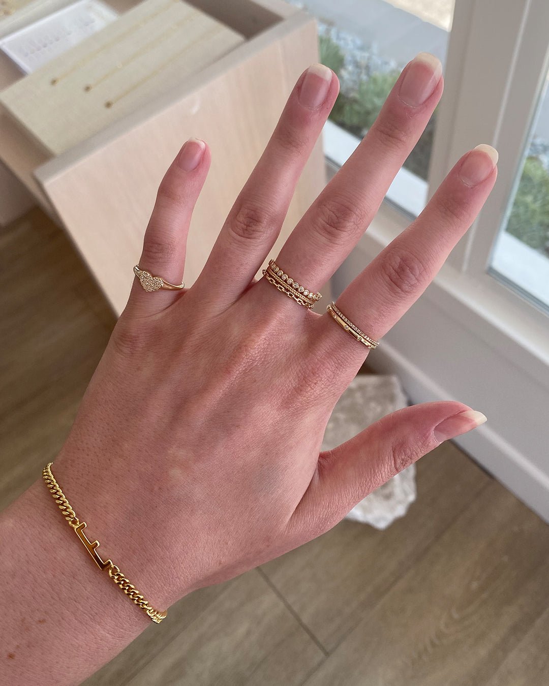 Woman wearing 14k gold rings and a gold plated alphabet bracelet.