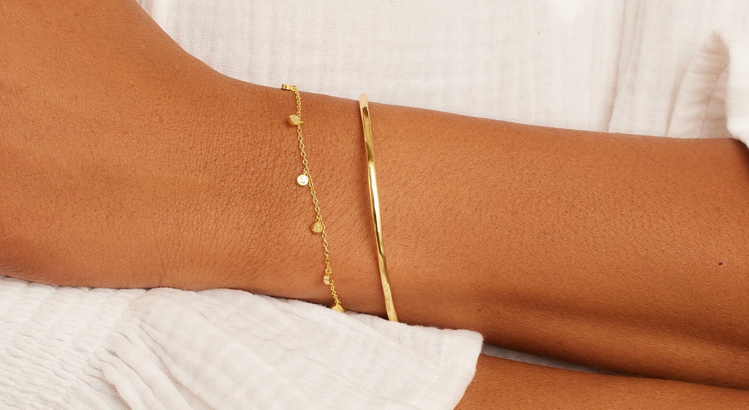 woman wearing a set of two gold bracelets
