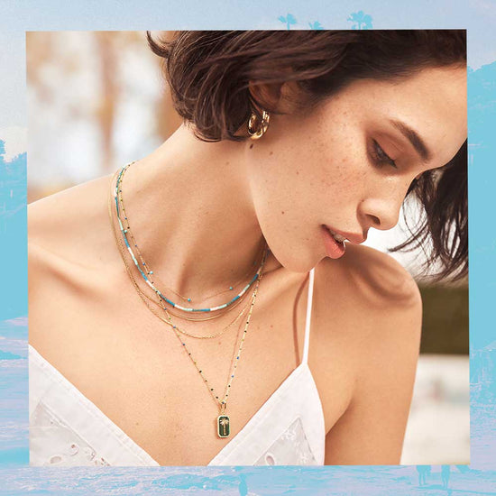 woman in white tank top with necklace layers