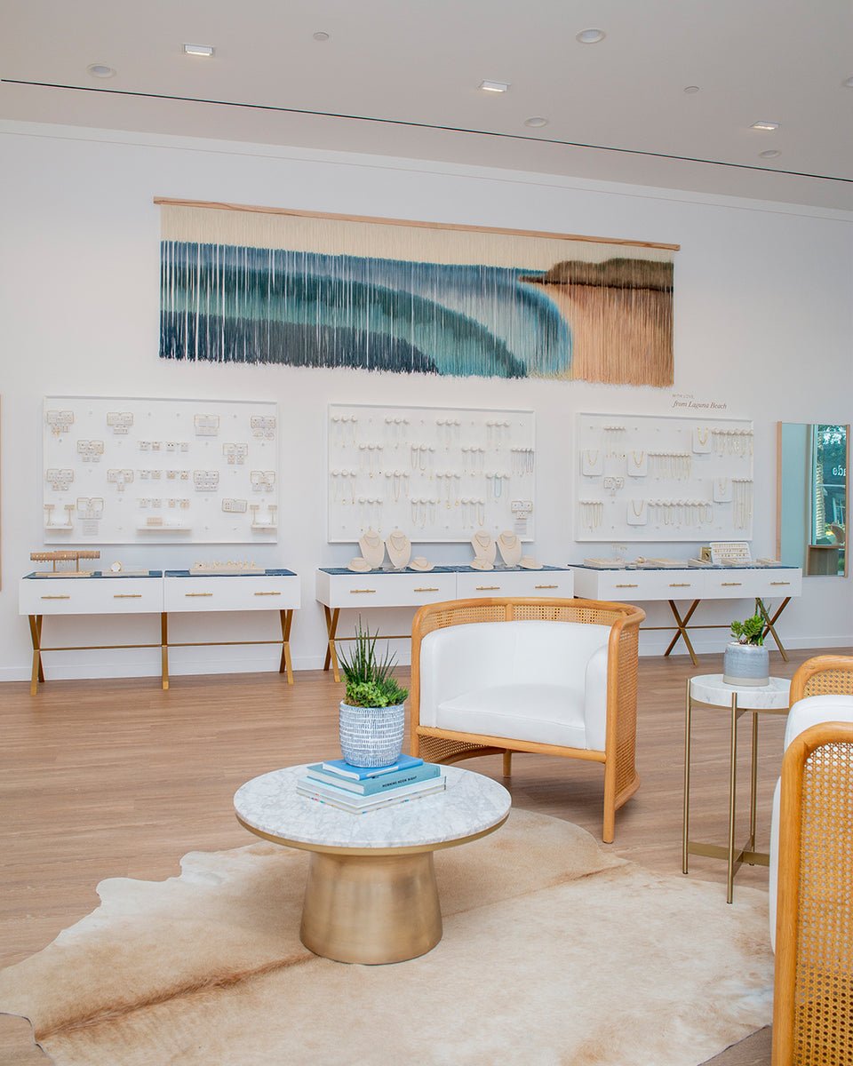 Jewelry wall with an ocean scape art piece and beachy style chairs