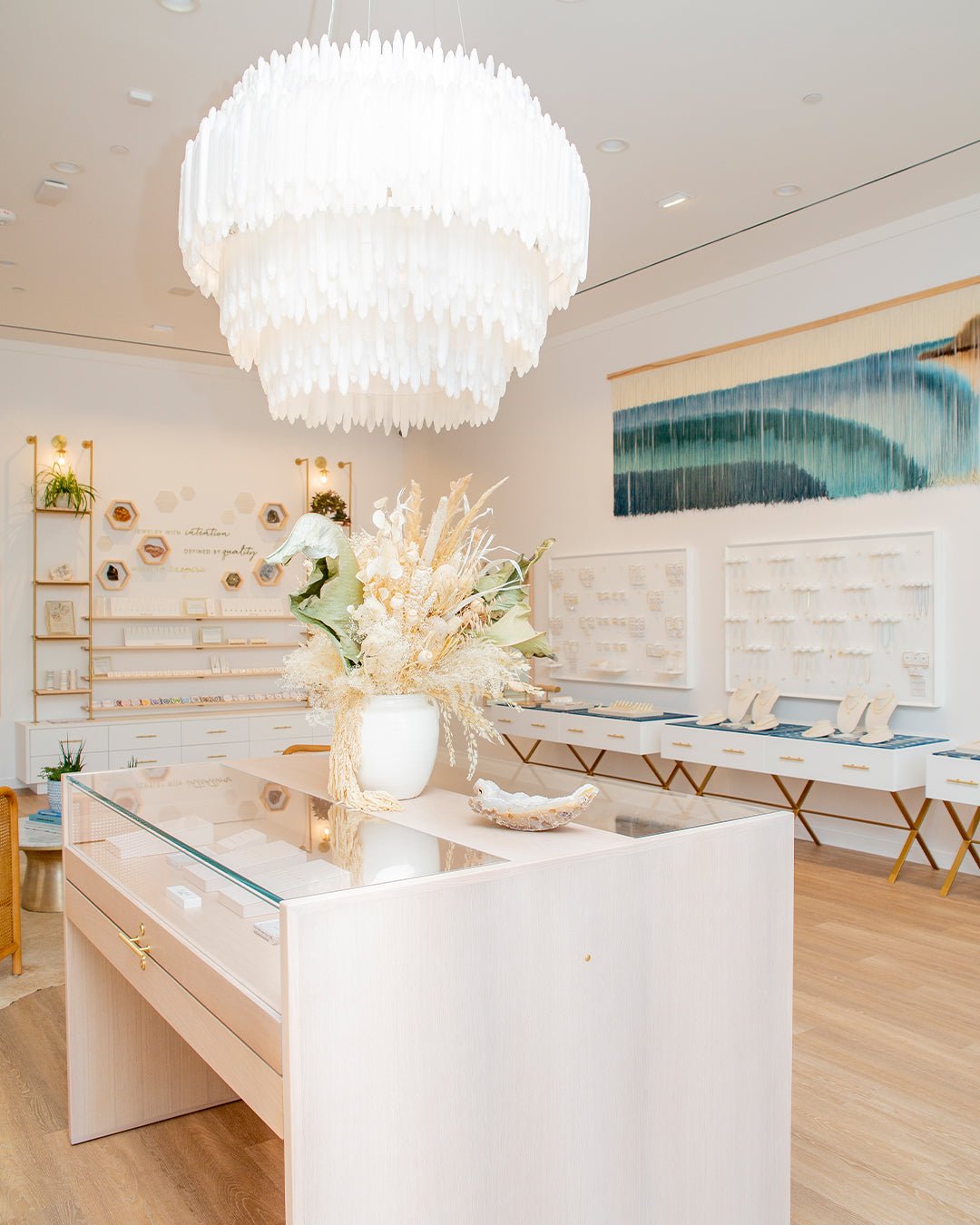 Light and bright store interior with large white chandelier over a jewelry case