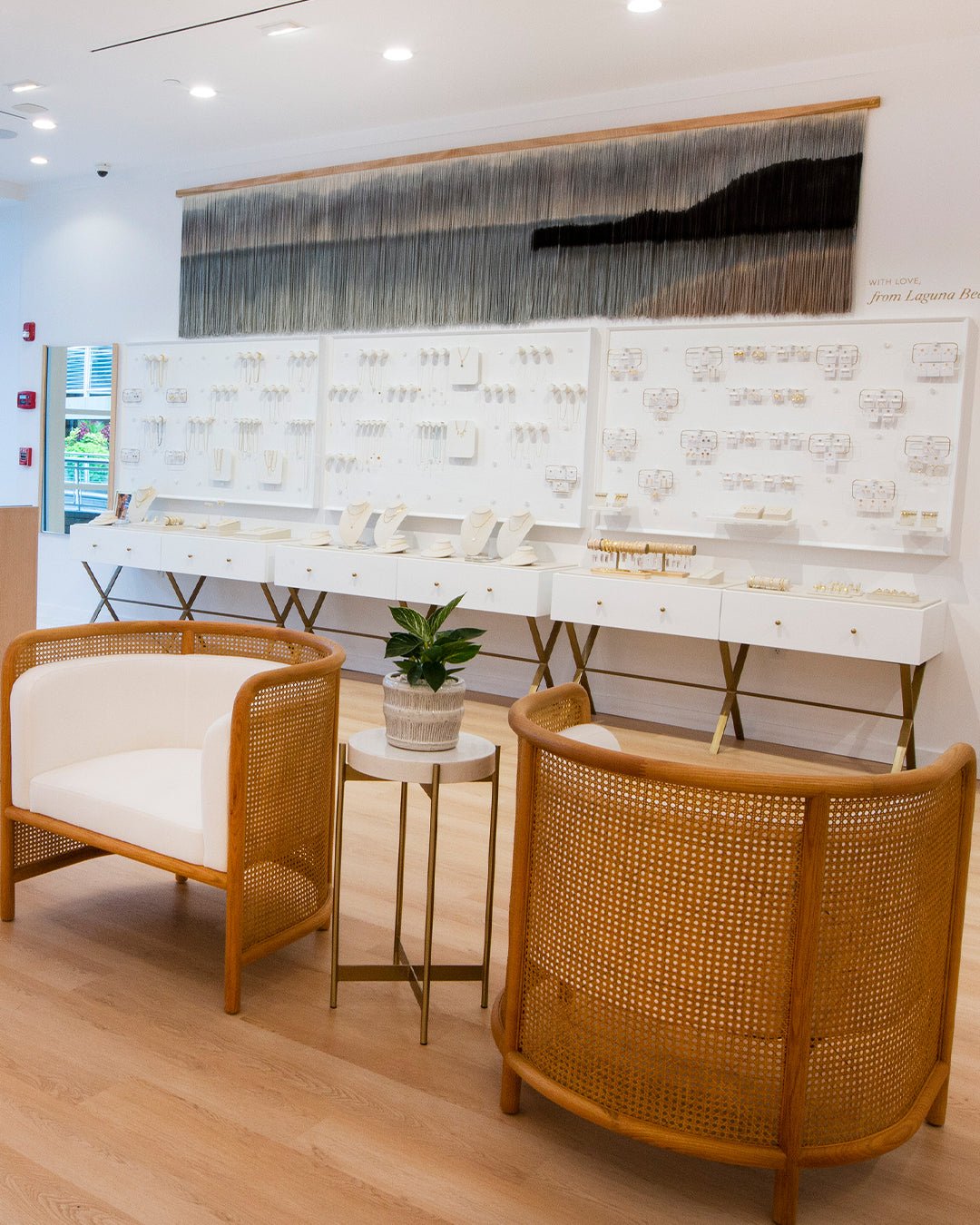 Interior of gorjana store with wooden chairs and white cushions. beachy vibes