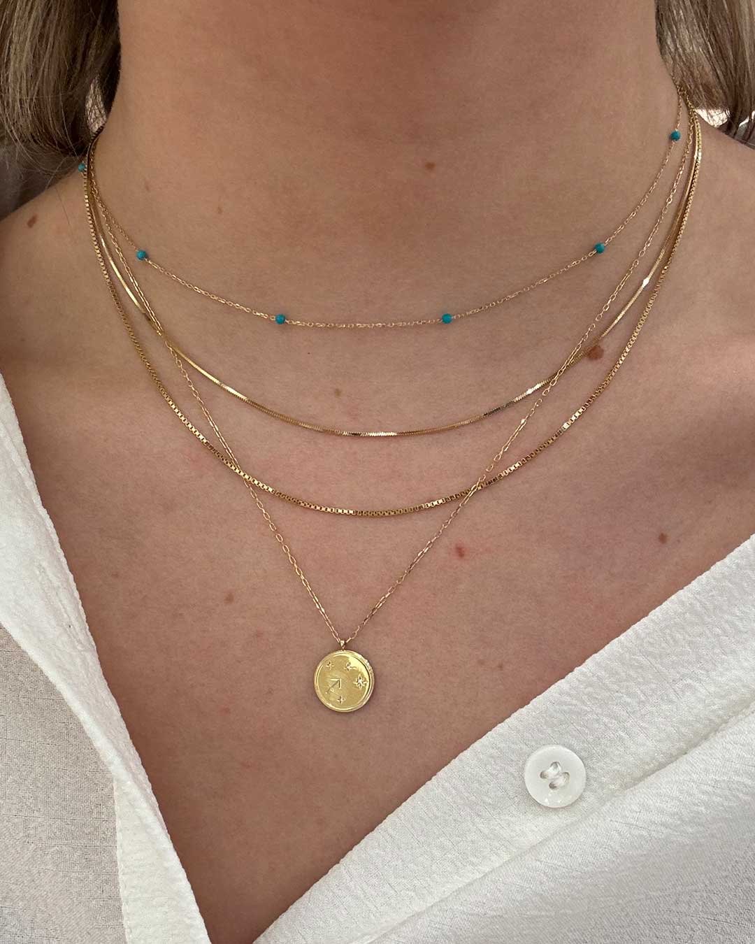 Stylist wearing The Turquoise Newport Necklace, 14k Gold Micro Mini Vence Necklace, 14k Gold Box Chain Necklace and Diamond Zodiac Necklace.