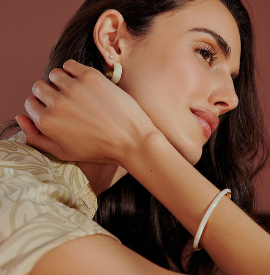woman in white marble paseo cuff bracelet and white marble statement hoop