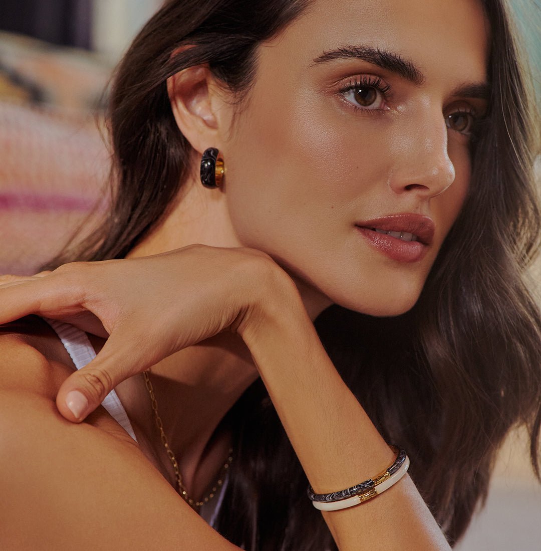 woman with bracelet stack on tanned wrist with statement hoop black marble earring