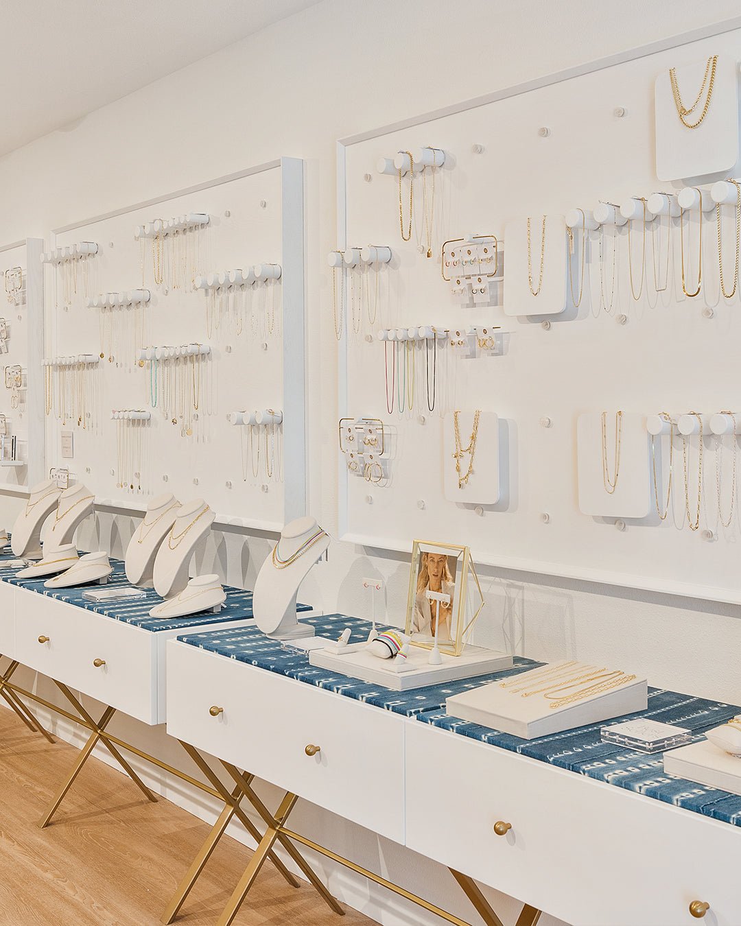 white wall filled with jewelry and cases below with jewelry stands