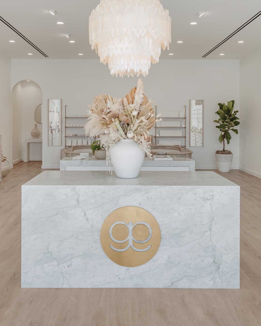 interior of gorjana store with marble counter with gorjana logo and big white chandelier