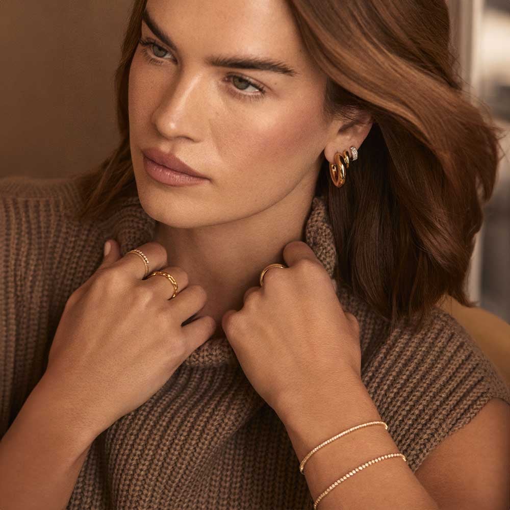 Woman wearing gold plated and solid gold rings, earrings and bracelets