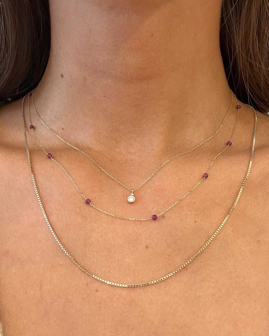 Woman wearing 14k gold birthstone necklaces 