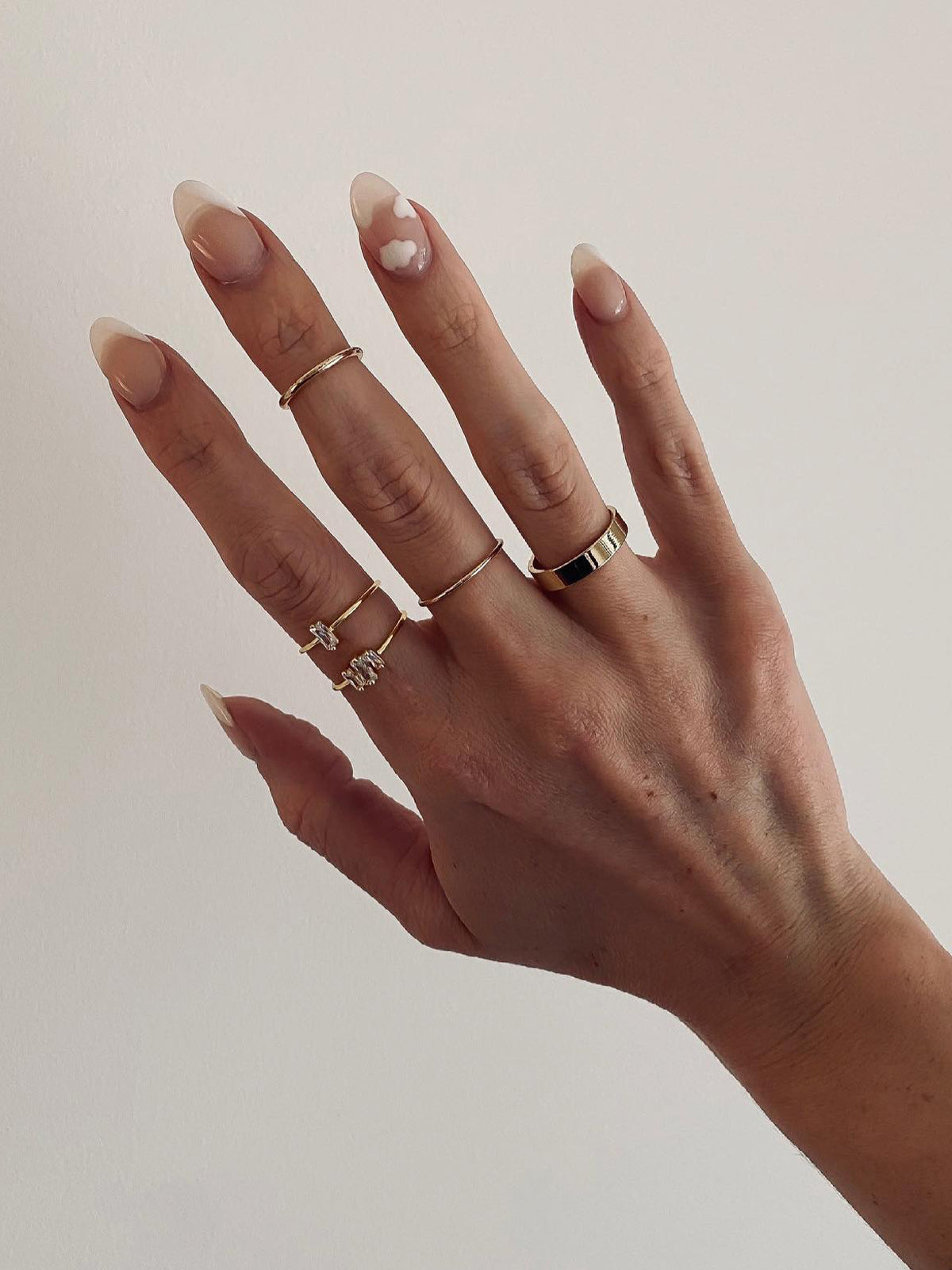 Woman wearing jeweled gol plated ring set, classic gold rings and a gold plated cigar band ring.