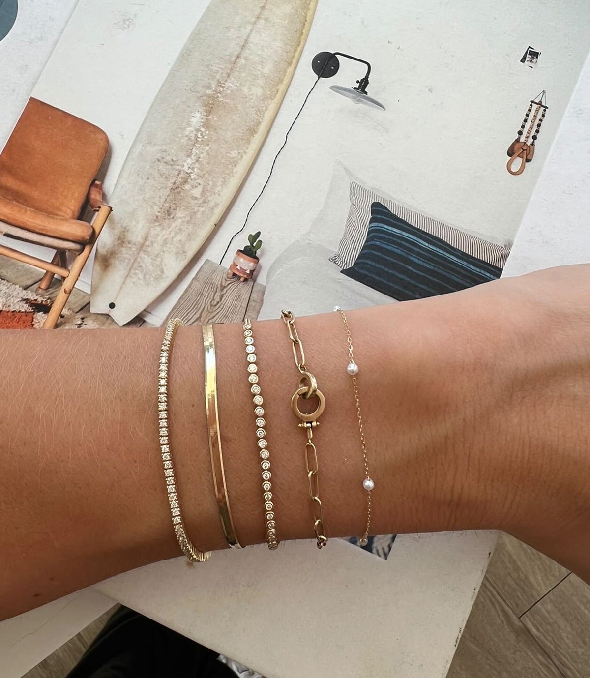Woman wearing 14k gold diamond tennis bracelets, a genuine pearl bracelet and 14k gold chain link bracelet 