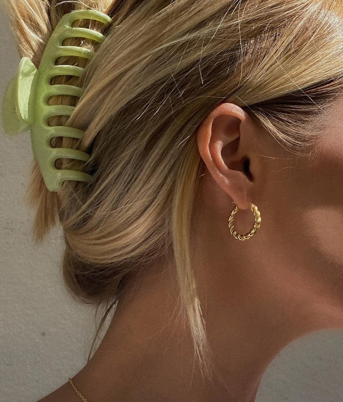 Woman wearing twisted gold plated hoops.