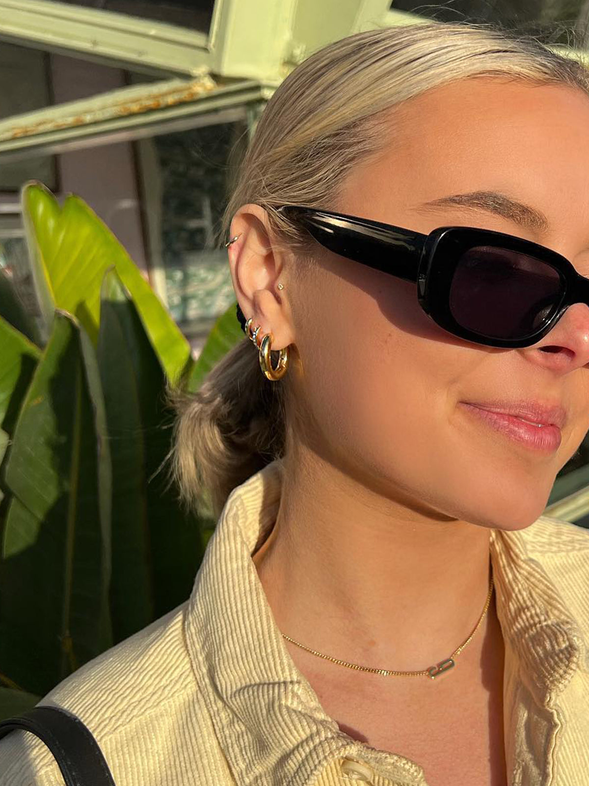 Woman wearing gold plated huggies and hoops.