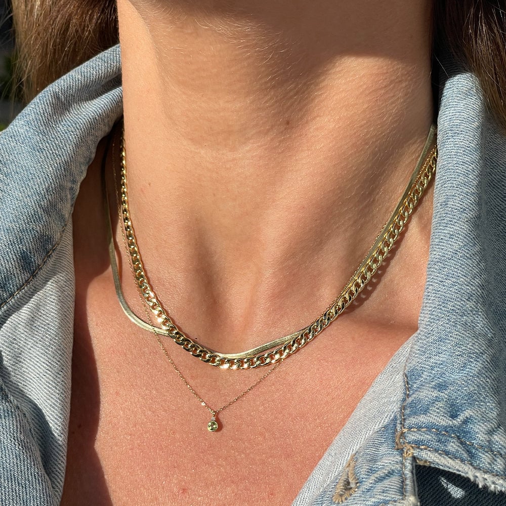Woman wearing layered gold necklaces.