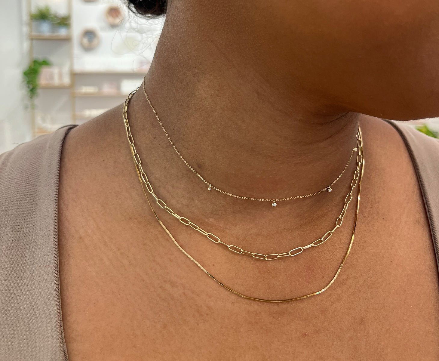 Woman wearing a 14k gold necklace and gold plated layered necklaces.