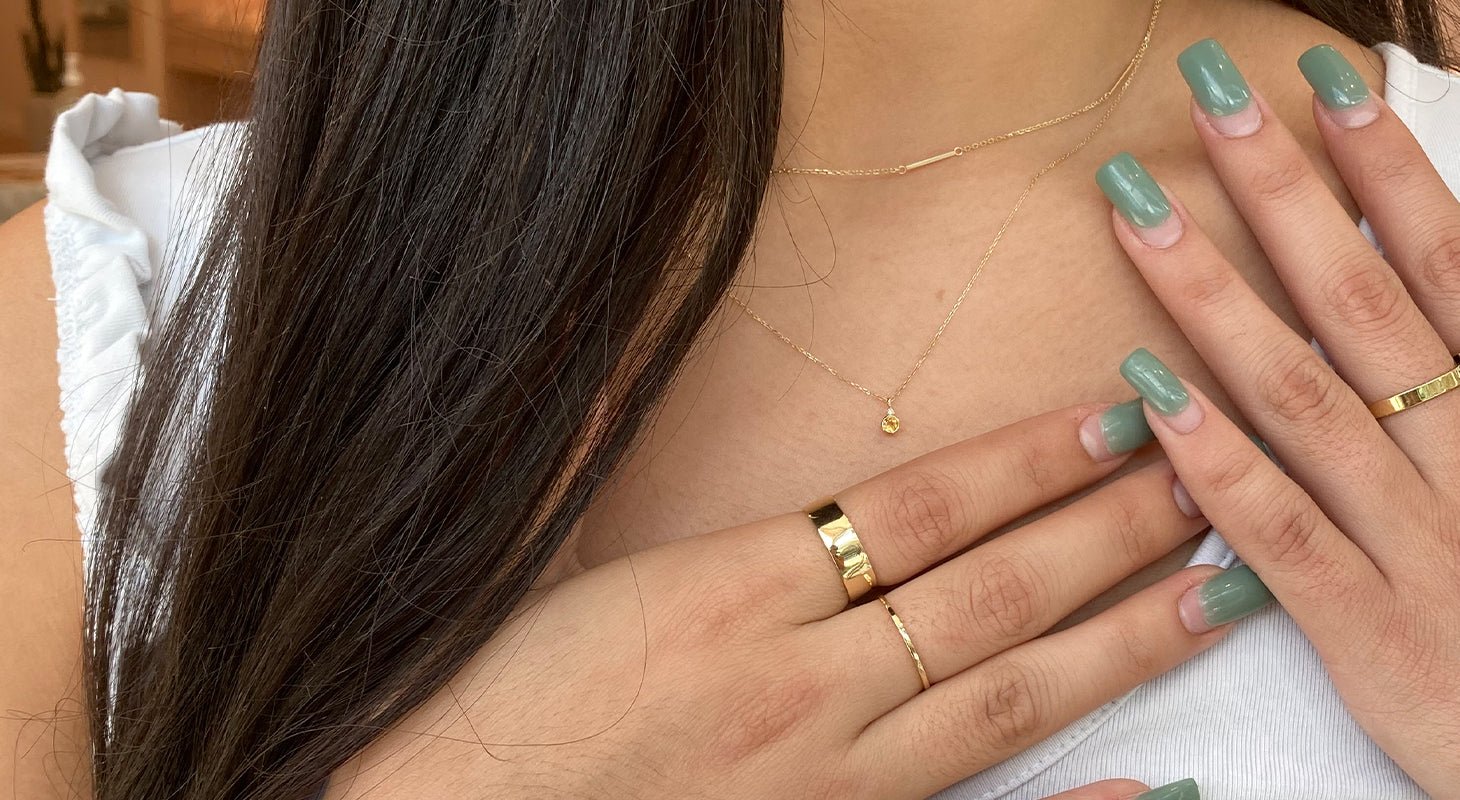 Woman wearing gold necklaces and gold plated stacking rings. 