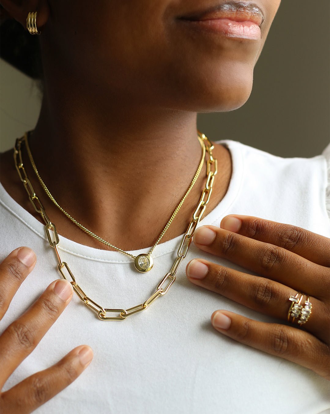 Woman wearing gold plated necklaces, earrings and rings.