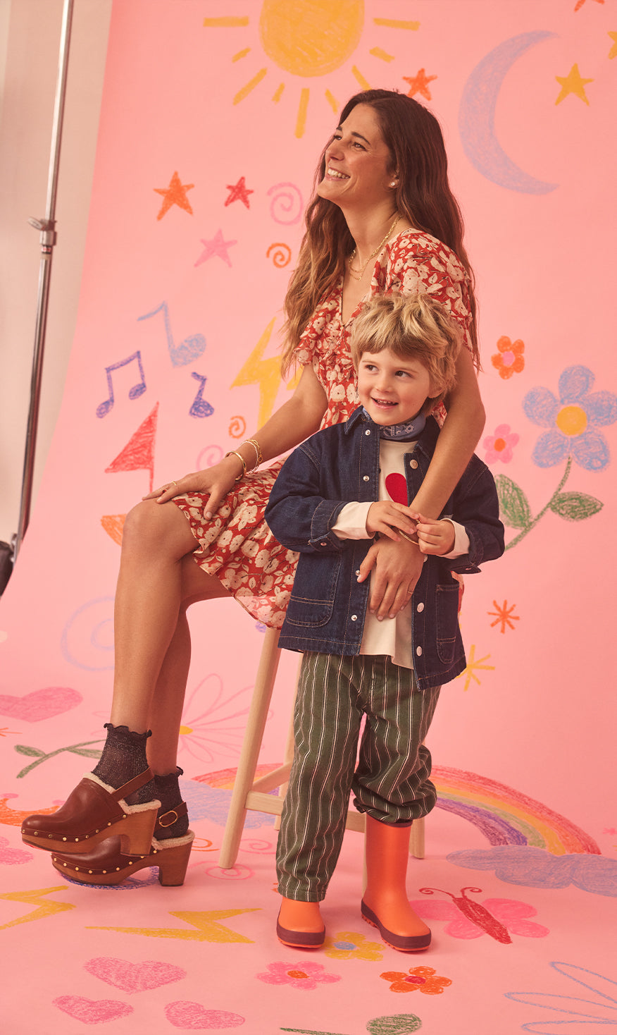 Ally & Sonny standing in front of a colorful, patterned wall with a pink background.
