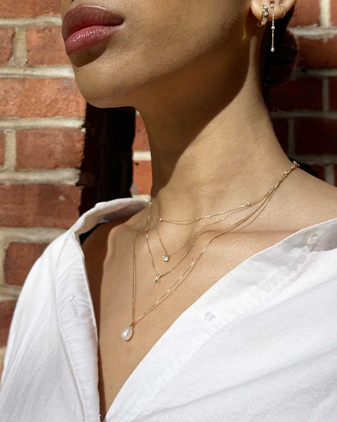 Woman wearing pearl and diamond necklaces and earrings. 