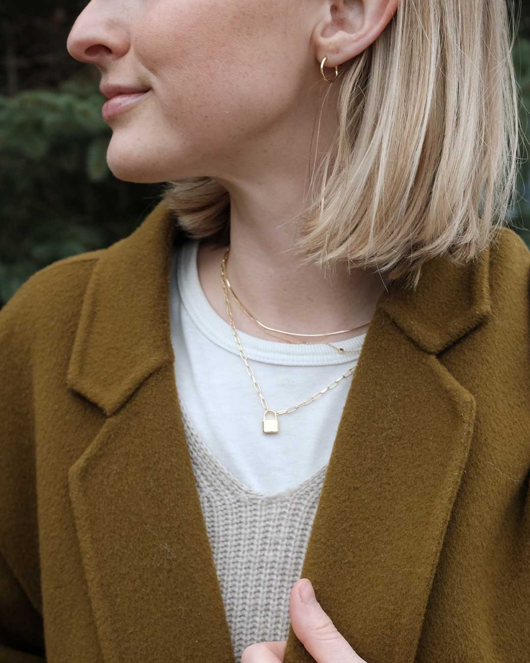 Woman wearing gold plated necklaces and solid gold huggies